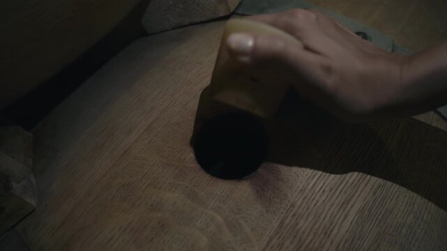 Worker screwing off the cap to open the wine barrel at the beverage production facility. Opening the wooden barrel full of alcoholic wine. Opening the barrel with fresh wine drink at the vinery.