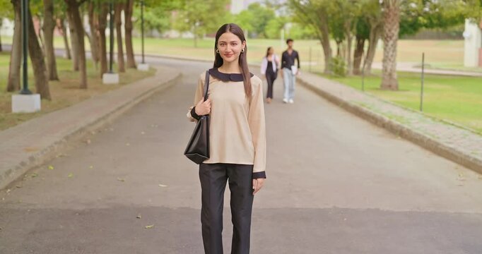 Indian happy young adult gen z proud smart lady female look camera cross arms standing outdoor campus area. Teen age pupil pretty girl fold hand wear bag staring cam do casual pose enjoy new day place