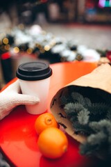 Festive holiday market display featuring pine branch bouquet, bright citrus fruits, warm coffee, and decorative lights