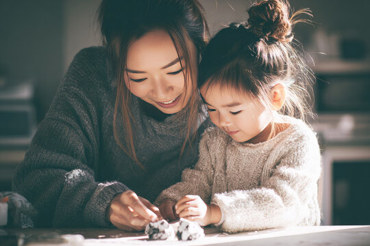 Asian mother child cozy sweater indoor natural light bonding creativity clay art happiness family togetherness smiling learning childhood parenting home love warmth hands activity concentration