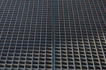 Symmetrical close view of a metallic grid pattern with square divisions.