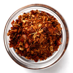 Top view of a glass bowl filled with crushed red chili flakes and dried spices. Spicy seasoning mix with hot peppers, paprika, and herbs for cooking, grilling, barbecue, and exotic recipes.