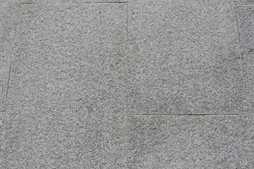 Gray granite paving slabs on a city street, background.