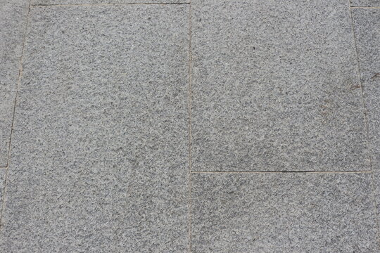 Gray granite paving slabs on a city street, background.
