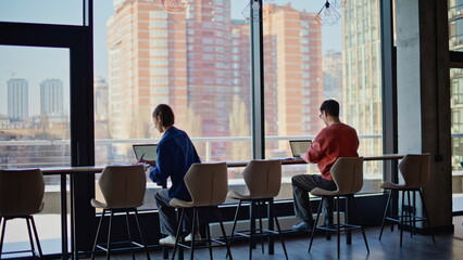 Fototapeta premium Students focused laptops screen making online homework in cafe table back view.