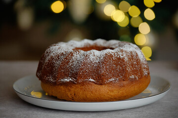 A ruddy cupcake on a plate with festive lighting in the background.