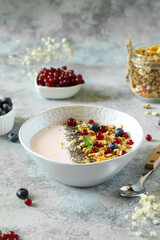 A mouthwatering breakfast bowl is artfully arranged with creamy yogurt, crunchy granola, and a medley of vibrant, fresh berries, all beautifully presented on a stylish gray countertop