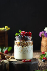 Delicious yogurt parfait with granola, berries, and mint displayed on a rustic wooden table in an indoor setting