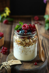 Savor a delightful yogurt parfait, beautifully layered with crunchy granola and plump, fresh berries, all enjoyed in a charming rustic environment
