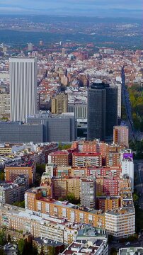 Vertical 4K drone video Madrid skyline with AZCA business towers above dense residential blocks to mountains. Epic aerial footage of Spanish capital's urban layers for mobile video social platforms.