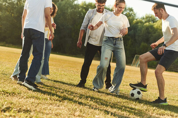 Fototapeta premium Summertime fun. Group of friends are playing soccer on the field
