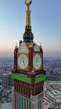 drone footage of Mecca, Saudi Arabia, filmed at sunset. The video captures the vast urban landscape with residential buildings, modern towers, and surrounding mountains bathed in golden hour light