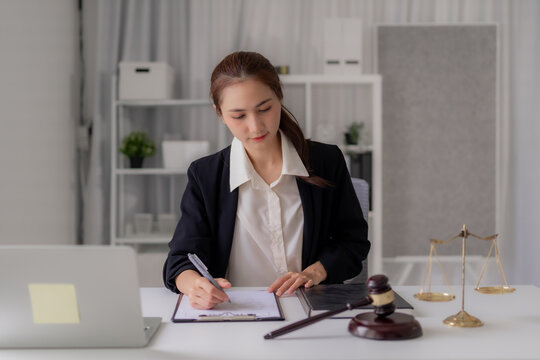 Asian Female Lawyer Drafting Legal Documents Law Firm Office Young Attorney Reviewing Contract Agreements Justice System Scales Gavel Courtroom Regulations