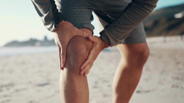 Man experiencing knee pain on a beach.