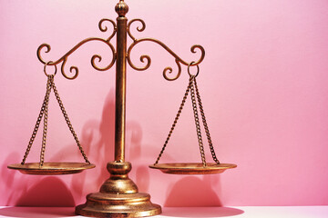 libra scale against pink background.
