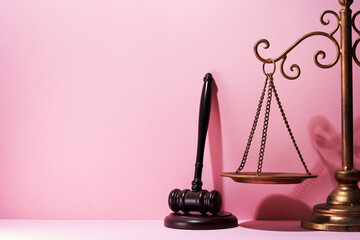 libra scale and gavel hammer against pink background.