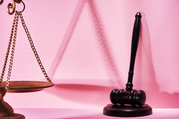 libra scale and gavel hammer against pink background.