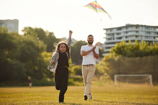 Front view, running with kite. Father with his little daughter are on the field