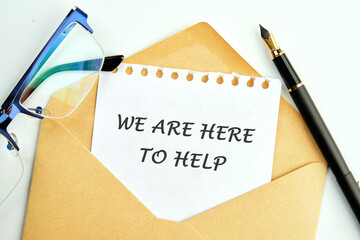 Simple Customer Support Concept . WE ARE HERE TO HELP an inscription on a piece of paper peeking out of an envelope next to glasses and a pencil