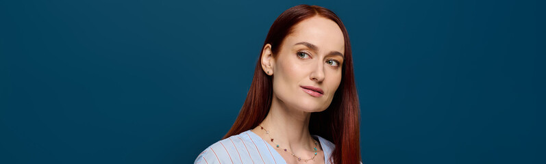 Portrait of a woman with vibrant red hair against a striking blue background