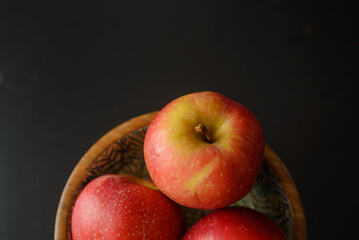Three delicious and healthy red ripe apples in a wooden bowl