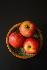 Three delicious and healthy red ripe apples in a wooden bowl