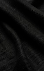 Close-up of dark fabric with subtle texture and folds, showcasing its luxurious drape and deep black hue