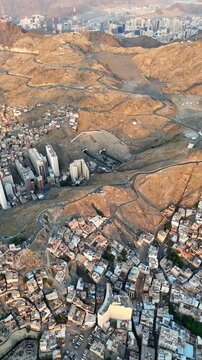 drone footage of Mecca, Saudi Arabia, filmed at sunset. The video captures the vast urban landscape with residential buildings, and surrounding mountains bathed in golden hour light