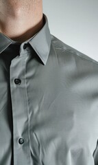Close-up of a man's gray, button-down collared shirt, showcasing the fabric texture and tailored fit of the collar and upper chest area against a neutral backdrop