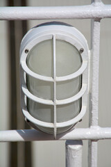Close up of a marine bulkhead light fixture, with a protective grid cover. a classic detail of a ships safety and lighting equipment.