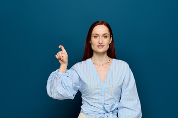 Red-haired language teacher demonstrating sign language in a vibrant blue setting