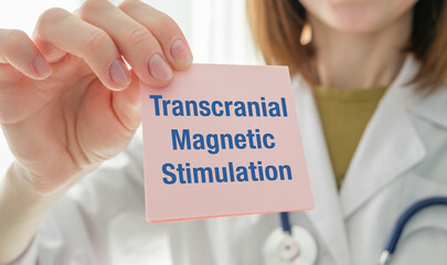 A person holding a card that says Transcranial Magnetic Stimulation. The card is blue and white