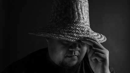 Man in straw hat front view holding brim with hand, black and white portrait style, concept of...