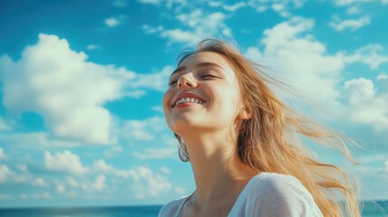 Naklejka premium Beautiful smiling young woman enjoying the feeling of freedom and happiness under a bright blue summer sky with clouds