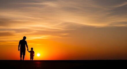 Silhouette of a father and son holding hands while walking on the beach against a beautiful orange sunset.
