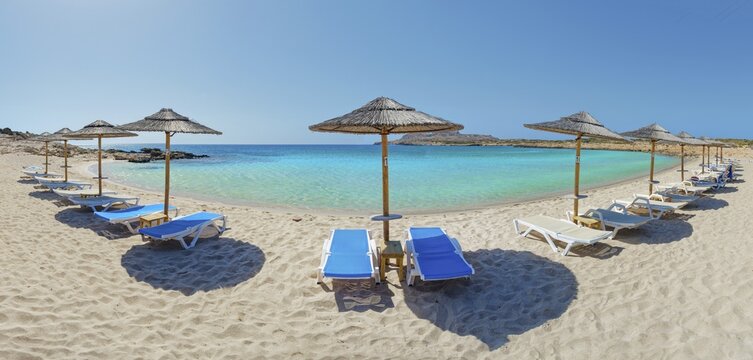 Sunny beach day at Diakoftis sandy beach with sun loungers under parasols in front of turquoise-coloured water, Diakoftis beach, Karpathos, Greece