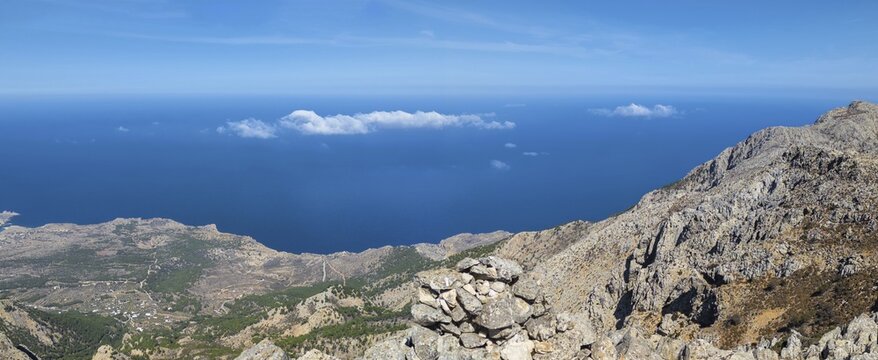 Behind the rocky promontory of the summit of Kali Limni, the bright blue sea of the west side of Karpathos spreads out, interspersed with clouds, hike to the summit of Kali Limni, Kali Limni, Lastos, Karpathos, Greece