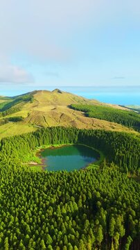 Hills, Forest and Lake Lagoa do Canario on Sunny Evening. Azores, Sao Miguel Island, Portugal. Aerial View. Drone Moves Forward. Vertical Video