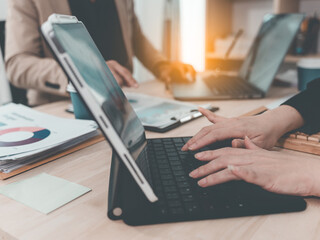 Fototapeta premium Colleagues analyzing data on documents and digital tablet at workplace Two business men working on a laptop and digital tablet with financial charts, graphs and data in the office