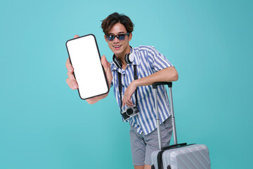Asian man traveler holding smartphone with blank screen and suitcase wearing casual vacation outfit with camera and headphones expressing travel technology and lifestyle concept
