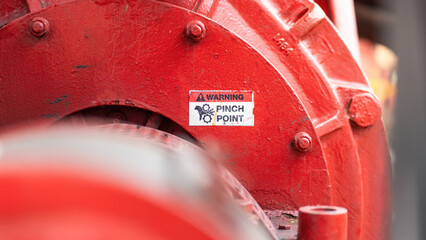 "Pinch point warning sign" hand and finger injury prevention alert that showed on the industrial equipment such as blender, pumping or milling machine. Safety sign in unsafe working place, close-up.