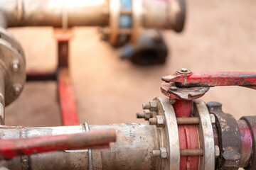 Handle controlling gate valve of water pumping unit which is used in oil field operation. Heavy industrial equipment object, close-up and selective focus at the valve handle.