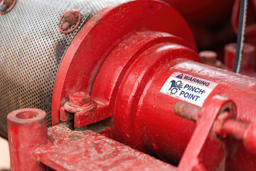 "Pinch point warning sign" hand and finger injury prevention alert that showed on the industrial equipment such as blender, pumping or milling machine. Safety sign in unsafe working place, close-up.