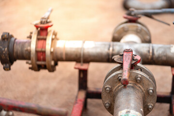 Handle controlling gate valve of water pumping unit which is used in oil field operation. Heavy industrial equipment object, close-up and selective focus at the valve handle.