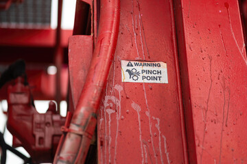 "Pinch point warning sign" hand and finger injury prevention alert that showed on the industrial equipment such as blender, pumping or milling machine. Safety sign in unsafe working place, close-up.