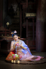 Pretty Asian Thai woman wearing traditional Thai dress costumes according to Thai culture at the ancient temple in famous tourist attraction in Thailand.