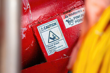 "Pinch point warning sign" hand and finger injury prevention alert that showed on the industrial equipment such as blender, pumping or milling machine. Safety sign in unsafe working place, close-up.