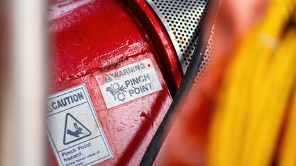 "Pinch point warning sign" hand and finger injury prevention alert that showed on the industrial equipment such as blender, pumping or milling machine. Safety sign in unsafe working place, close-up.