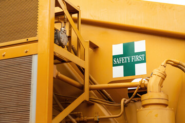"Safety first" warning sign on the crane vehicle or industrial machine part. Safe working practice with risk condition. Close-up with selective focus.
