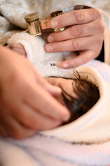A baby's christening ceremony, hands gently holding a small religious item.